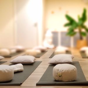 Lichte ruimte met yogamatjes, meditatiekussens en opgerolde dekens klaargelegd voor het weekend